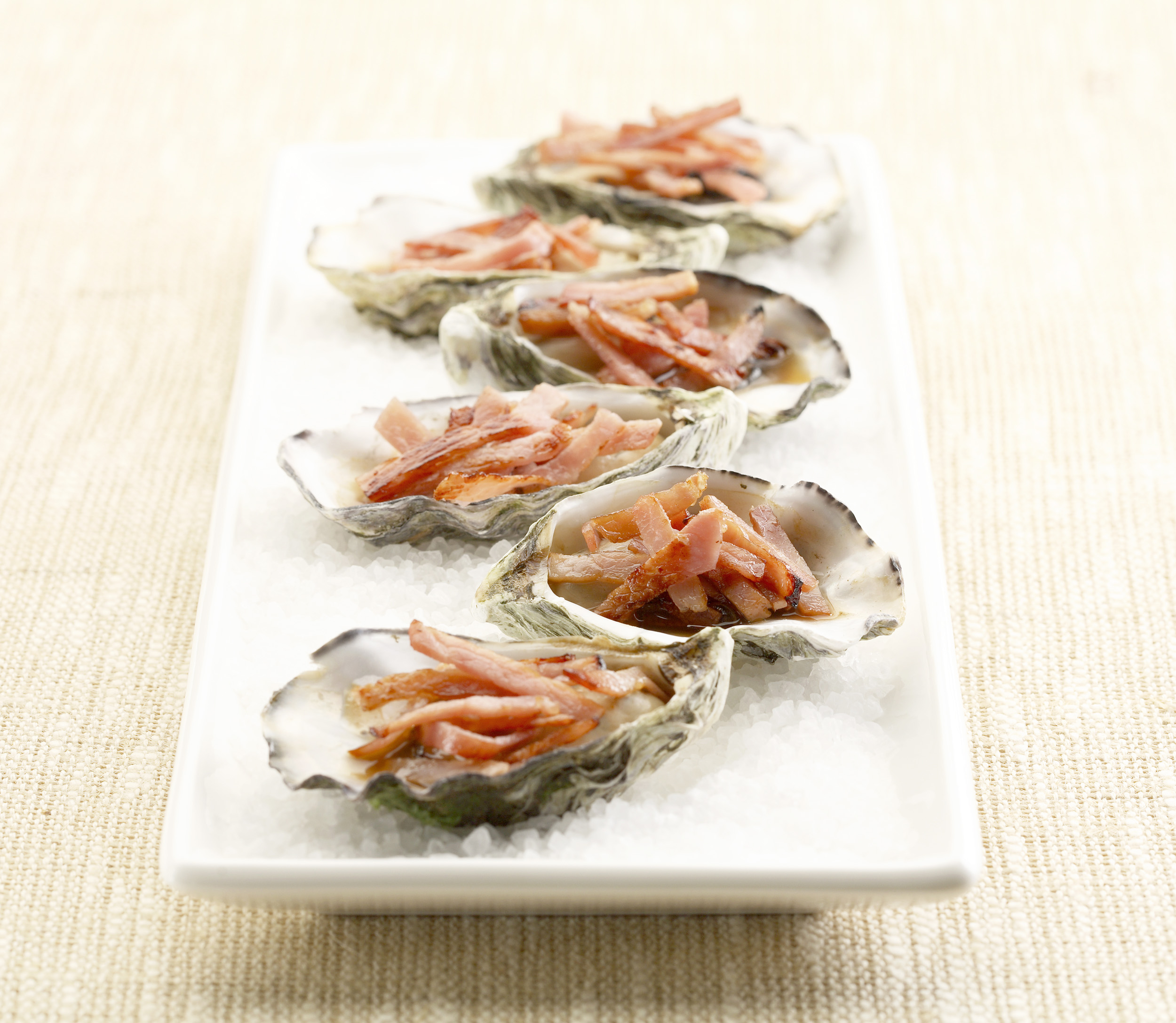 Plated Oysters Kilpatrick on a cream background. Paul Scott, food photography.